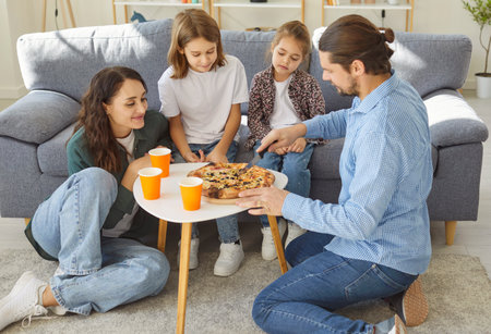 Happy parents with two children enjoy eating pizza during family dinner at home, sharing lunch together in a cozy setting filled with joy and connection in a warm domestic environment.の写真素材