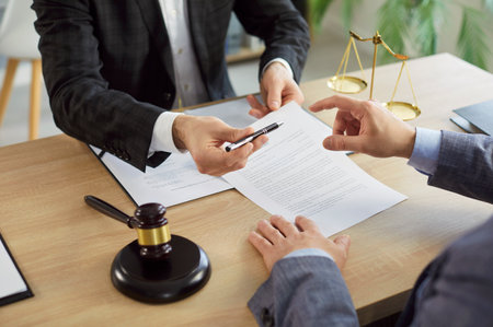 Man signing a contact with male advocate sitting on workplace. Male lawyer working in office during consultation with client sitting at desk with judges gavel and scales. Legal law concept. 4k videoの写真素材