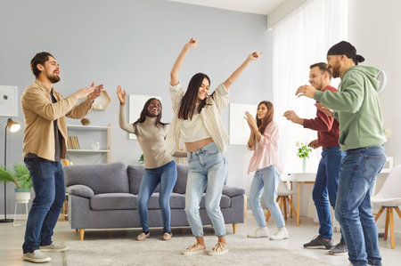Dancing friends group at home, people enjoy fun, happy dance entertainment, party gathering, students wearing formal wear, event celebration, enjoyment, amusement, enjoyable gathering in living roomの写真素材