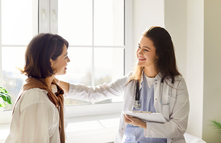 Kind young female practitioner doctor in shoulder supporting gesture clinic talking to patient woman, explaining checkup result, medical screening, giving consultation on appointment, recommendationの写真素材