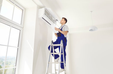 Man worker or a technician, installing, inspecting and maintaining the home or office air conditioner, ensuring its optimal performance and efficiency for comfortable living conditions.の写真素材