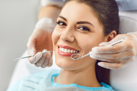 Portrait of happy smiling woman looking cheerful at camera sitting in dentistry clinic during medical check up. Close up of female patient treating teeth at dentist office. Teeth care concept.の写真素材