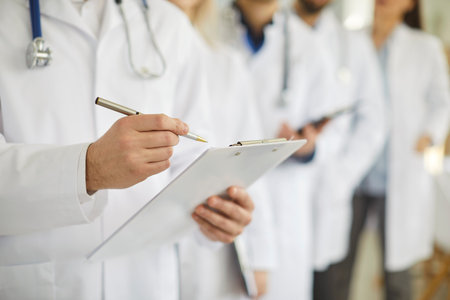 Professional doctor wearing uniform taking notes in clipboard journal, physician therapist with stethoscope, practitioner filling medical documents, new patient form, illness history, prescriptionの写真素材