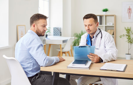Male serious doctor in white medical uniform consulting man patient, GP giving consultation to client, discuss illness in hospital, healthcare, explaining prescription, disease prevention and careの写真素材