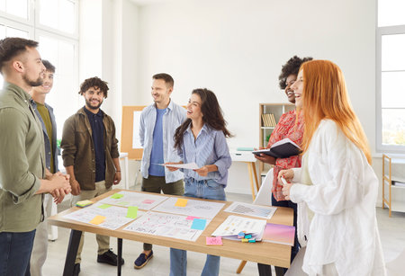 Group of happy laughing young successful business people in casual clothes working together discussing job projects and start ups at workplace in office. Corporate business and teamwork concept.の写真素材
