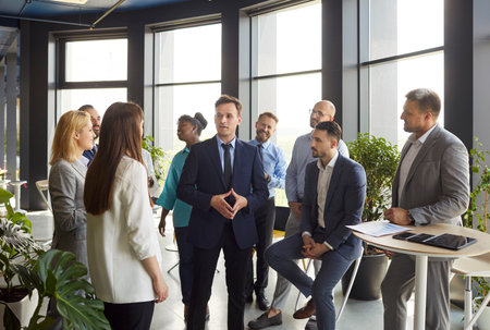 Business man, company team leader coach mentor talking to diverse business people in office to explain strategy at corporate group meeting, staff boss instruct interns at briefing, brainstorm ideasの写真素材