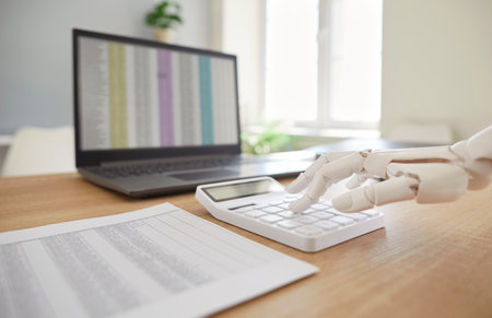 Robotic hand, mechanical arm counting on calculator, accounting machining processes, laptop screen checking stock market data, powered accounting software trading stocks information for growthの写真素材