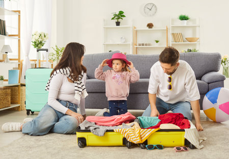 Family vacation happy packing suitcase together at home, planning, preparing for travel or recreation, parents, children dreaming of enjoyment or sea relaxation, going on leisure trip, summer journeyの写真素材