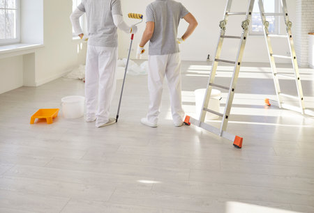 Painters team standing with paint rollers, construction workers, professional service men wearing uniform for preparation, painting, tasks for room repair, color wall in apartment flat, renovationの写真素材