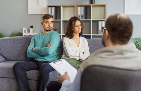 Family couple attends therapy session with psychologist during relationship conflict or quarrel, receiving assistance from doctor in a professional setting with focus and care daily.の写真素材