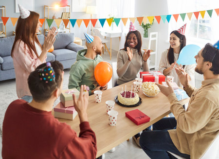 Friends happy birthday candle cake celebration, friendly group portrait applauding on party together for event, smiling people gathering making fun, enjoy time, wishing great happiness, joy, amuseの写真素材