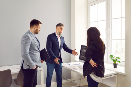 Business team having an important work meeting in the office. Group of young and mature people discussing their business strategy. Mature man making a presentation and using a modern computerの写真素材