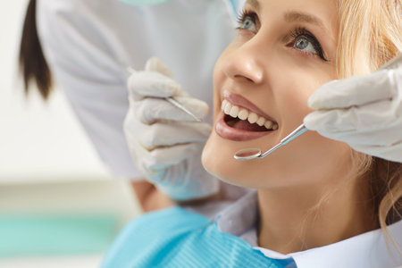 Doctor dentist or nurse examining woman patient in clinic, using dental instrument for oral care, providing dentistry service and medicare in a professional atmosphere with attention.の写真素材