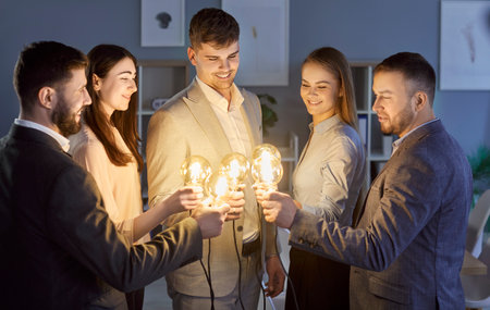 Positive business people in team hold light bulb in office, symbolizing idea and innovation with creative collaboration, focusing on work and teamwork in a professional setting with vision.の写真素材