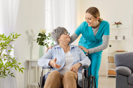 Professional female nurse gives help and support handicapped old lady in wheelchair, takes care of senior people in nursing house, have pleasant communication with each other. Nursery conceptの写真素材