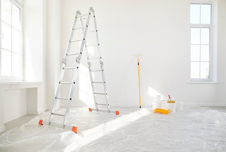 Step ladder with bucket and paint roller standing in empty light room in new house or flat with freshly painted white walls with copy space. Renovation process in apartment. Home repair concept.の写真素材