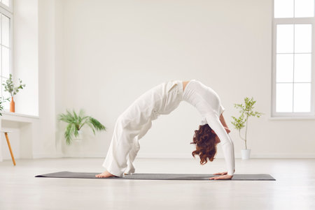 Woman is engaged in yoga in the gym, doing stretching exercise or asana, bridge pose, during workout sport training. She demonstrates strength, flexibility and balance, enhancing overall fitness.の写真素材