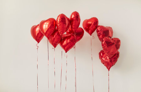 Vibrant red heart-shaped balloons float gracefully against a neutral background, adding a touch of joy and romance. Ideal for events such as Valentines Day or anniversaries.の写真素材