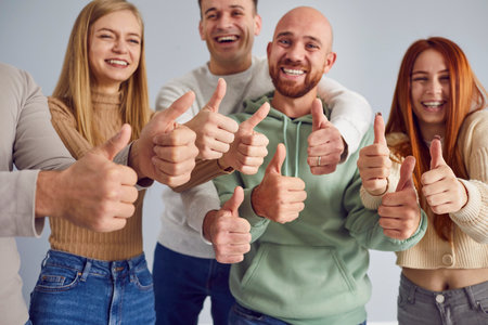 Group of young happy people showing thumb up gesture of approval, encouragement, raising thumb in agreement. Express yes, statement, cool idea or action, friends accept common suggestion togetherの写真素材