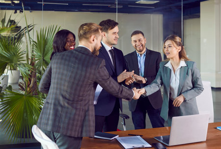 Business people diverse group in office encouraging thanking happy employee for good job, shaking hand, meet new worker, getting promotion, showing respect, applause of colleagues, leader introducingの写真素材