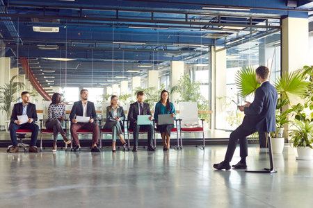 Businessman conducting a meeting or presentation for a team of business people in an office. He is actively talking with colleagues about work related matters. Communication in a professional setting.の写真素材