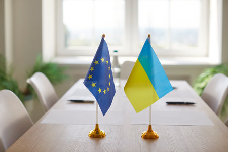 European Union and Ukraine flags standing on table in boardroom symbolizing international negotiations, unity and partnership. The concept of diplomacy, relations. agreement and cooperation.の写真素材