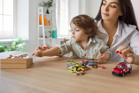 Positive mother and son enjoy playing a board game together during family leisure time at home, creating fun and entertainment in a cozy setting with a focus on bonding and shared moments of joy.の写真素材