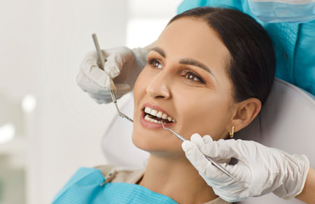 Doctor dentist or nurse checking woman patient oral care during hospital visit, offering aid and support with dentistry in a professional setting with focus on health and attention.の写真素材