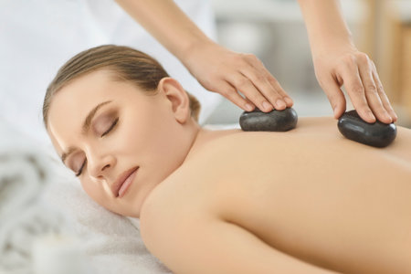Hot stone back spine massage, spa and beauty salon woman cosmetologist, beautician relieves tense muscles, reduce pain, calm, pleasure, rejuvenate, relax, treatment procedure, improve female healthの写真素材