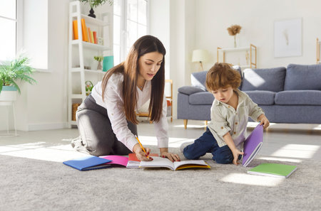 Happy mother and child engage in drawing together during leisure time at home, fostering inspiration and education through learning in a cozy family setting with a focus on creativity.の写真素材