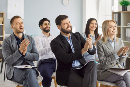 Happy friendly diverse employees applauding congratulating with business achievement, great work results or job promotion, business people cheering sitting in modern office, recognition, appreciationの写真素材