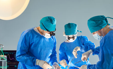 Concentrated surgeon team, medical practitioner group of professional medical doctors, surgical people performing surgery, doing operation, procedure on patient, wearing surgical gown, cap, face maskの写真素材