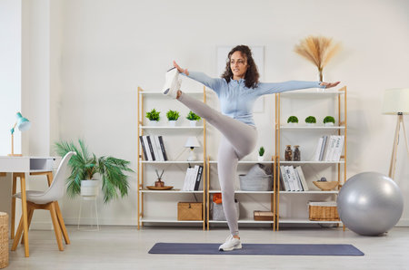 Portrait of a sporty athletic young woman exercising at home on the fitness mat. Young girl doing sport exercises in the living room. Healthy lifestyle, wellness and training concept.の写真素材