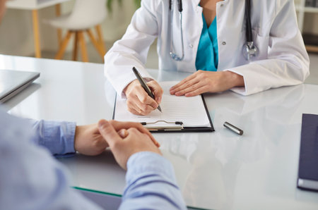 Female doctor, general practitioner filling paper medical records consulting patient in clinic, GP talking to discuss, checkup results with client at meeting hospital, share treatment plan, therapistの写真素材
