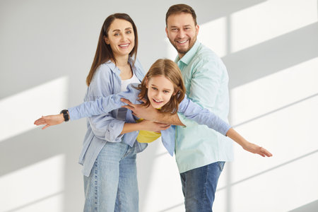 Happy young family of three having fun and playing with child boy isolated on gray background. Mother, father and little cute son spending time together enjoying weekend indoors.の写真素材