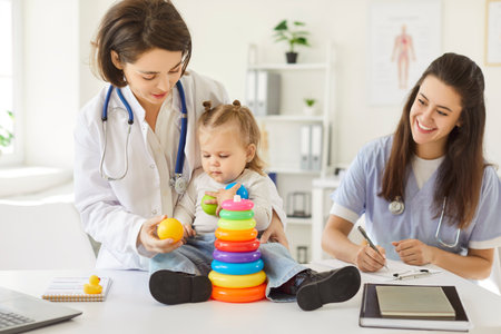 Pediatrician doctor and nurse playing with a young girl patient using toys during a hospital appointment. Promoting support and creating a comfortable environment during a medical visit.の写真素材