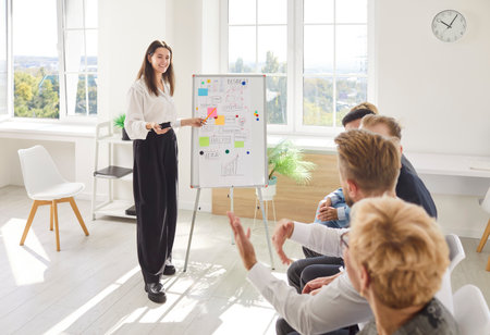Professional businesswoman conducting a meeting, briefing, or presentation for a group of professionals in an office, fostering communication and teamwork within the business people team.の写真素材