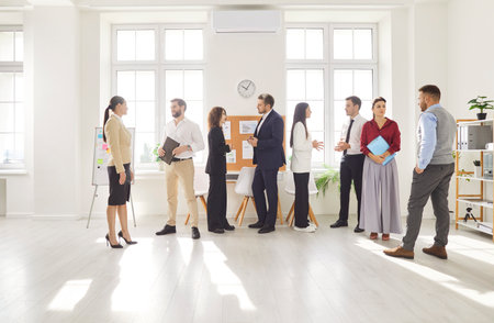 Group of young confident business people men and women talking after a meeting or a conference. Company employees working and discussing job and work projects in the office. Team work concept.の写真素材