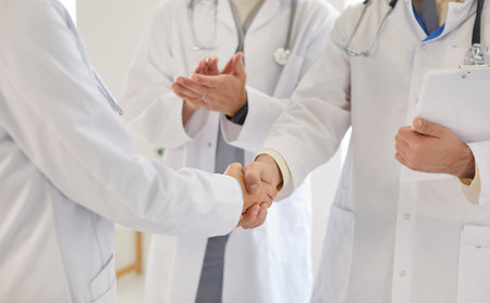 Closeup of doctors shaking hands reaching agreement in treatment or finishing conference standing in clinic. Successful team of medical staff in uniform make a deal on meeting. Health care concept.の写真素材