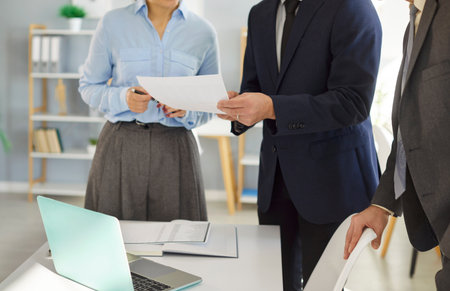 Business coworkers working together on research and accounting tasks in an office meeting, reviewing documents and contributing to company goals. The teamwork emphasizes productivity and partnership.の写真素材