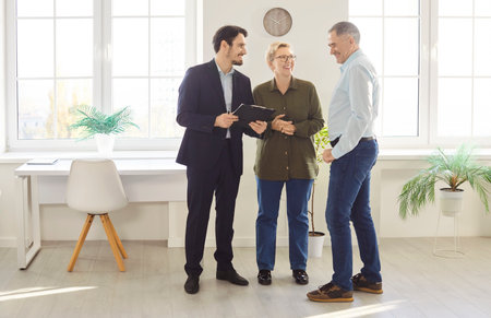 Elderly family couple tours a home with a real estate agent or realtor, considering purchase or rent. Deal involves detailed inspection and evaluation before deciding on the property.の写真素材