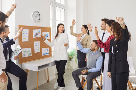 Group of business people in a meeting, raising hands to ask questions during an office presentation. Team of colleagues highlights collaboration, teamwork, and active engagement in work discussions.の写真素材