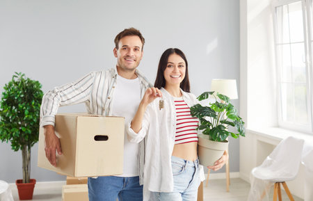 New home moving, happy laughing family couple holding key, buying flat, celebrate moving day holding box with stuff, having fun, enjoy home relocation, dreaming packing, decorating planningの写真素材
