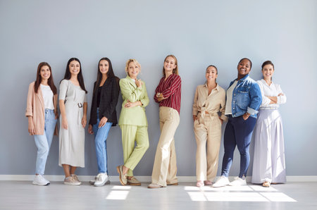 Portrait of a happy and diverse multinational group of business women standing together in an office against a gray background. People teamwork, team unity, and professional collaboration.の写真素材