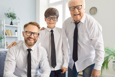 Portrait of three generations of men posing for camera wearing white shirts and ties. Elderly man,...
