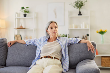 Portrait of a happy senior woman resting on a sofa at home. Grandmother positive mood, relaxation,...