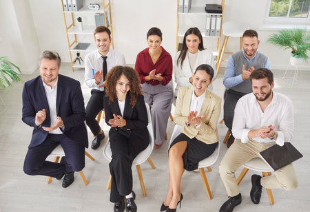 Happy diverse office employees applauding congratulating team with business achievement, great work results or job promotion, business people meeting in modern office, corporate teambuilding gatherの写真素材
