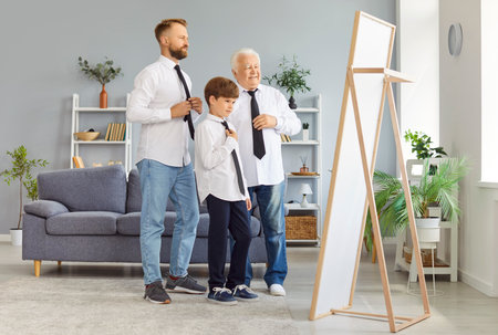Grandfather, father, and son dress in shirts and ties while looking in the mirror at home. The family moment, celebrating Father Day, highlights bonding during this special day together.の写真素材