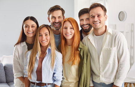 Group of happy smiling young people friends or colleagues in casual clothes standing together and...
