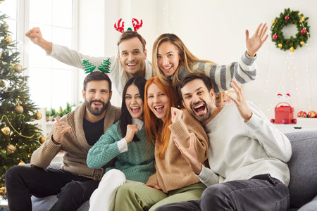Portrait of a positive group of friends celebrating Christmas or New Year at home. Joy and togetherness, showing a happy crowd enjoying the holiday party in a festive and warm atmosphere.の写真素材
